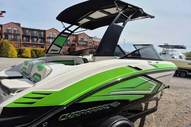 Slide: The Image of 2017 Chaparral Vortex 203 VRX boat with vibrant green accents, parked near brick buildings. - 3
