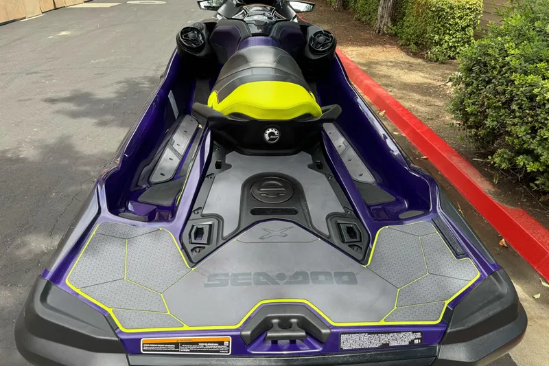 Slide: The Image of 2021 Sea-Doo RXT-X 300 in vibrant purple and yellow, parked on pavement. - 10