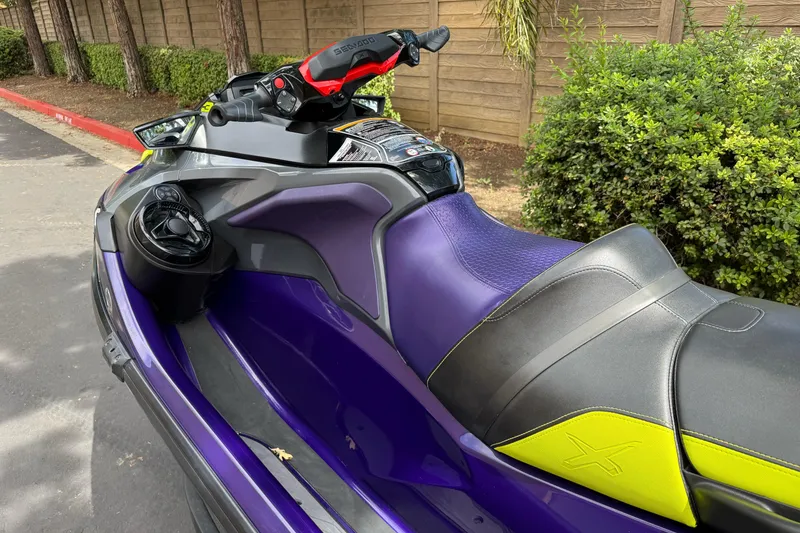 Slide: The Image of 2021 Sea-Doo RXT-X 300 jet ski with purple and black seat, parked outdoors. - 4