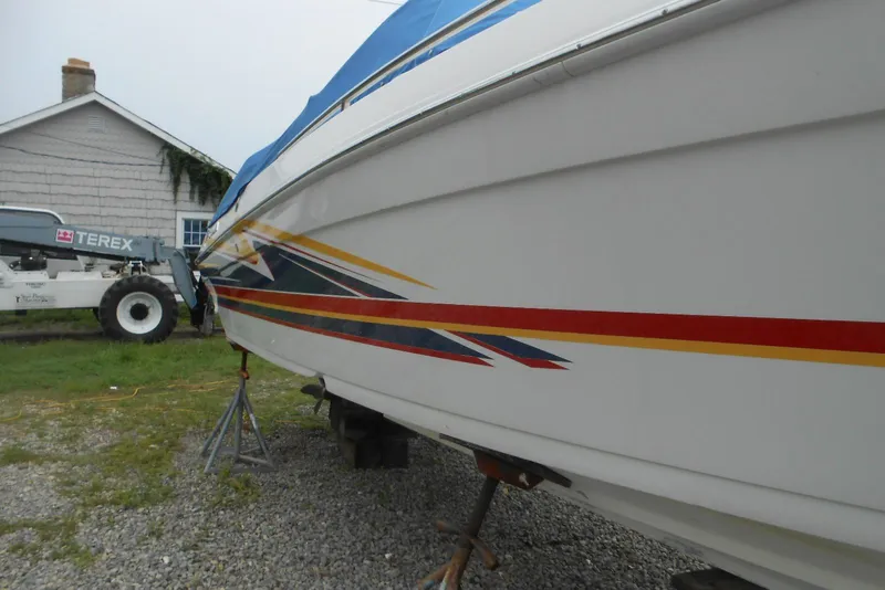 Slide: The Image of 2003 Formula 271 FASTech boat with colorful graphics, parked on gravel near a house. - 3