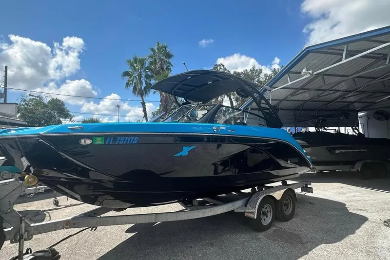 Slide: The Image of 2023 Yamaha Boats 222XD on trailer, blue and black design, parked outdoors under clear sky. - 0