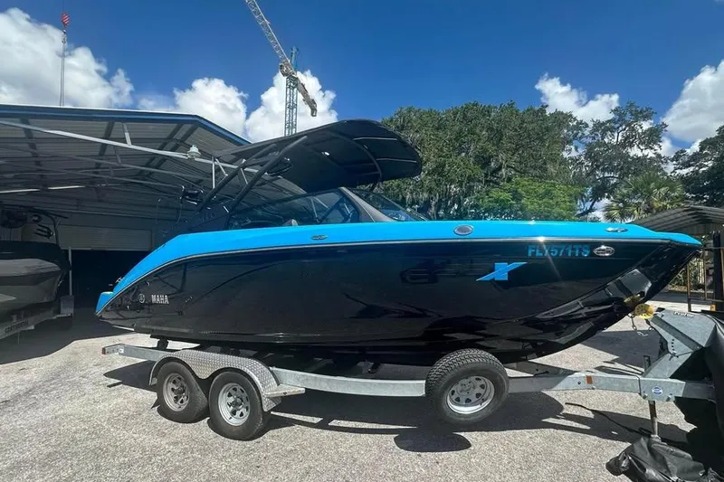 Slide: The Image of 2023 Yamaha Boats 222XD on trailer, blue and black design, parked outdoors. - 1
