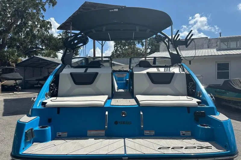 Slide: The Image of 2023 Yamaha Boats 222XD, blue exterior, rear view, docked under sunny skies. - 12