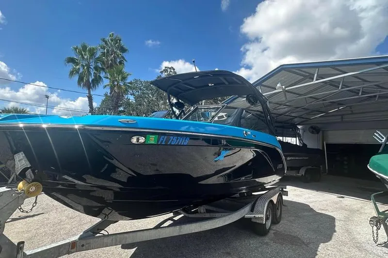 Slide: The Image of 2023 Yamaha Boats 222XD on trailer under sunny sky near palm trees. - 2