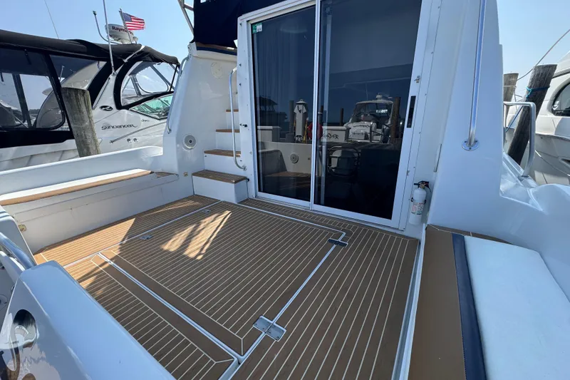 Slide: The Image of 1997 Mainship 40 Sedan Bridge yacht deck with sliding glass doors and wooden flooring. - 12