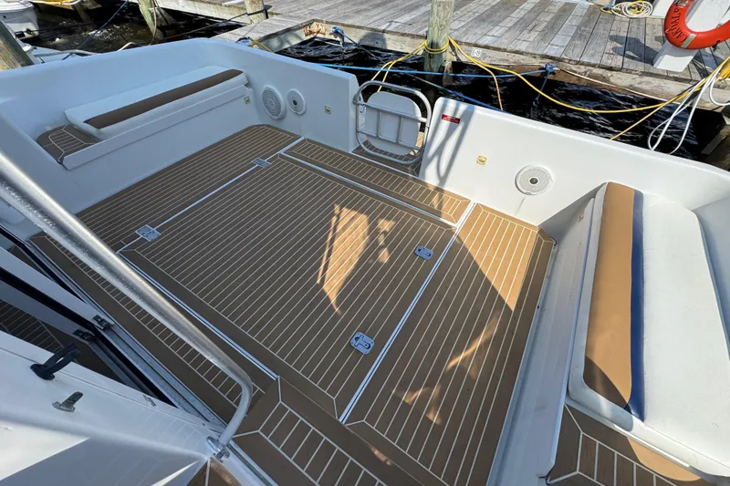 Slide: The Image of 1997 Mainship 40 Sedan Bridge boat deck with wood-patterned flooring and cushioned seating. - 13