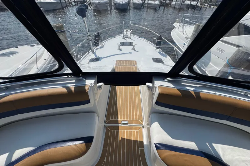 Slide: The Image of 1997 Mainship 40 Sedan Bridge interior with cushioned seating and wooden deck, docked at marina. - 21