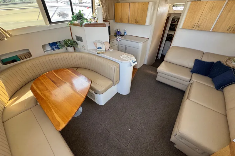 Slide: The Image of Interior of 1997 Mainship 40 Sedan Bridge with beige seating and wooden table. - 22