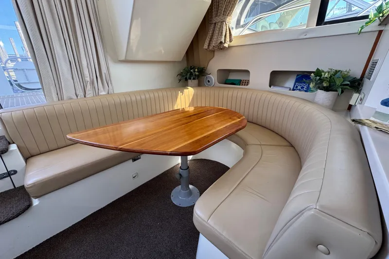 Slide: The Image of 1997 Mainship 40 Sedan Bridge interior with curved seating and wooden table. - 24