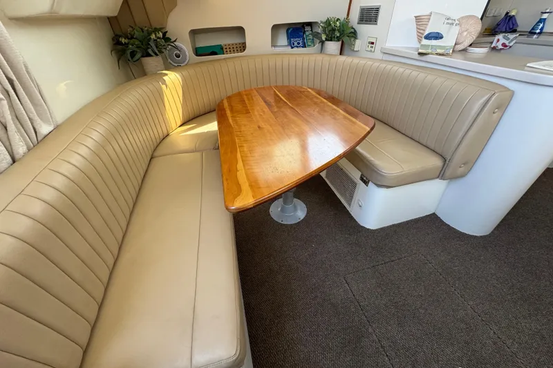 Slide: The Image of 1997 Mainship 40 Sedan Bridge interior with beige leather seating and wooden table. - 25