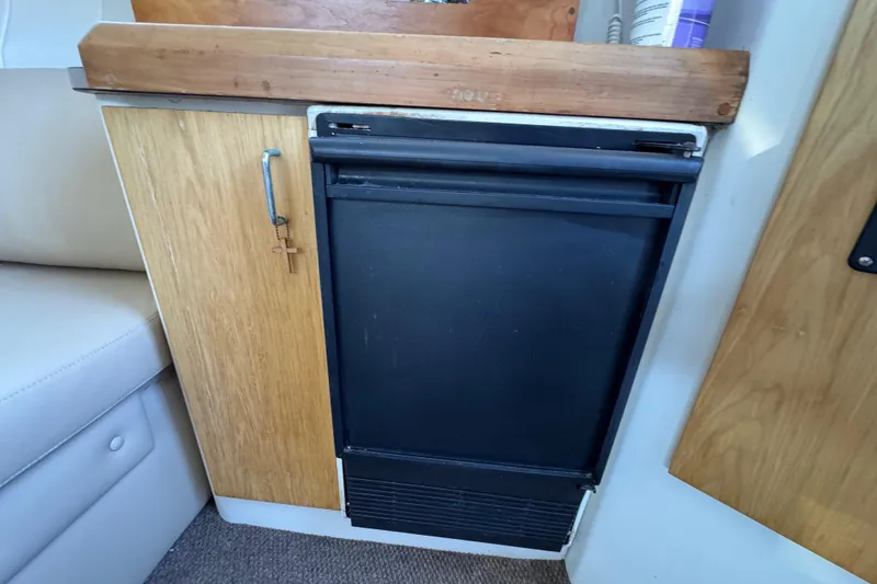 Slide: The Image of 1997 Mainship 40 Sedan Bridge interior with compact black refrigerator and wooden cabinetry. - 27