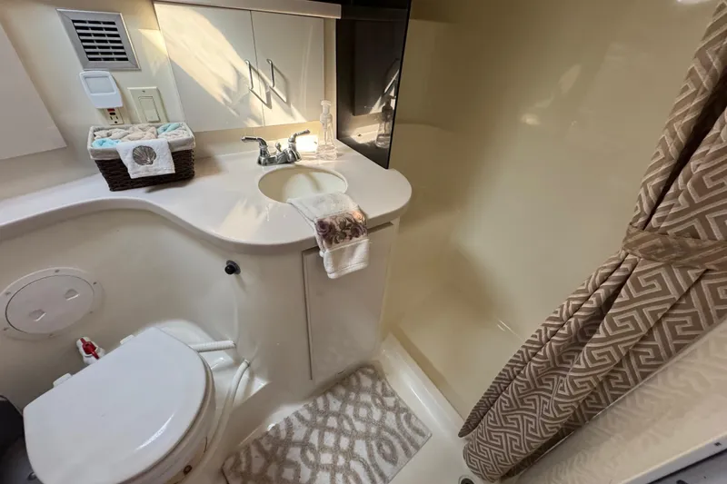 Slide: The Image of Bathroom interior of 1997 Mainship 40 Sedan Bridge with sink, toilet, and shower curtain. - 32