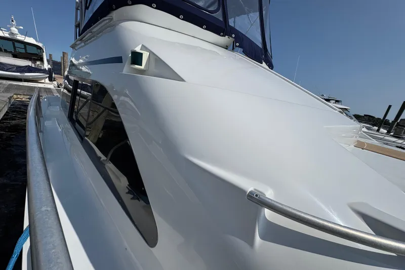 Slide: The Image of 1997 Mainship 40 Sedan Bridge yacht docked, showcasing sleek white exterior and modern design. - 5