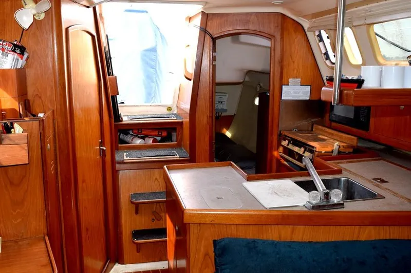 Slide: The Image of Interior of a 2001 Hunter 340 sailboat with wooden cabinetry and compact kitchen area. - 27