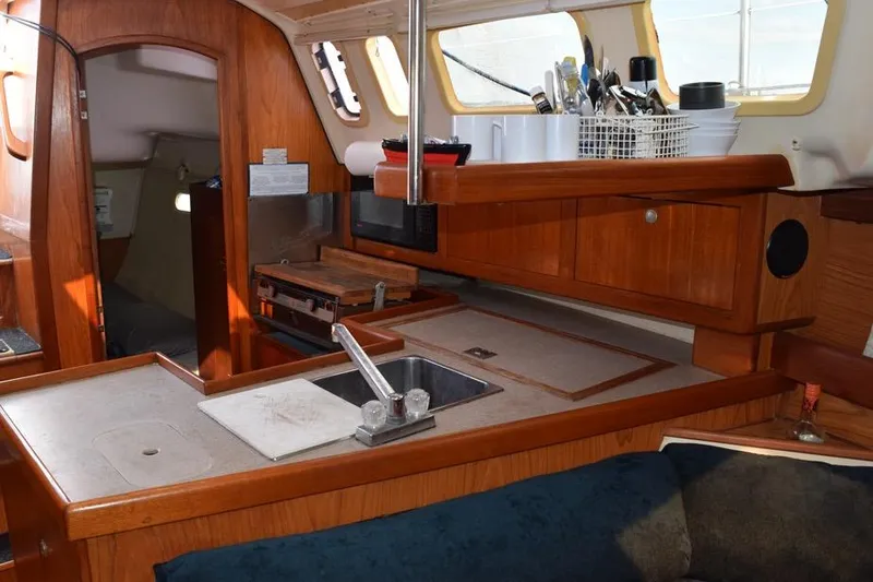 Slide: The Image of Interior of a 2001 Hunter 340 sailboat, featuring a compact wooden kitchen area. - 29