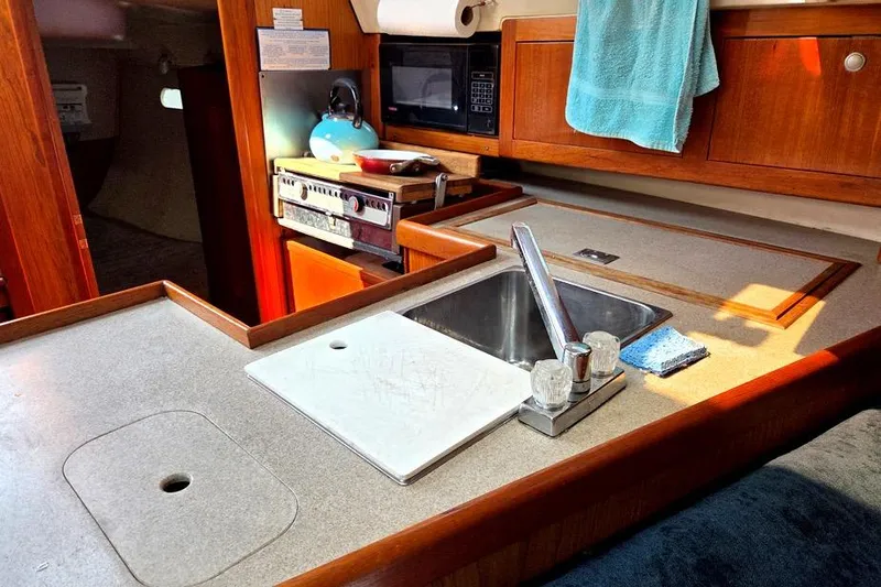 Slide: The Image of 2001 Hunter 340 yacht kitchen with sink, stove, microwave, and cutting board. - 30