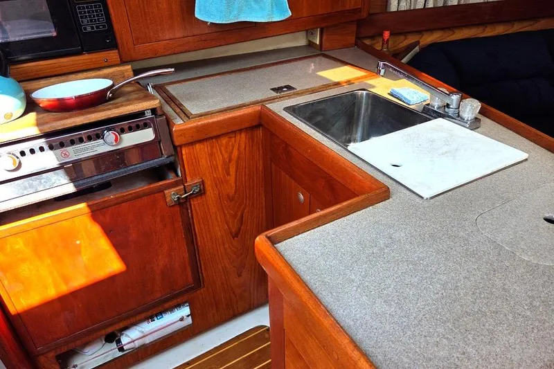 Slide: The Image of 2001 Hunter 340 yacht kitchen with stove, sink, and wooden cabinetry. - 31
