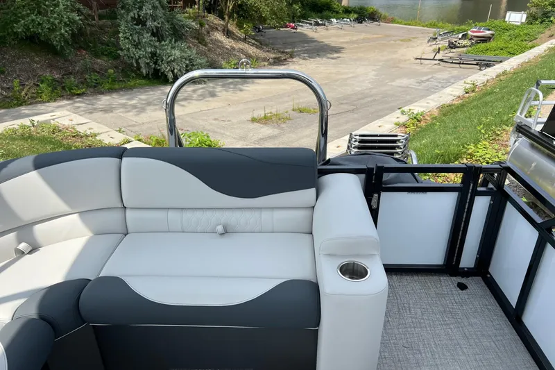 Slide: The Image of 2026 Tahoe TRITOON 2185 boat interior with plush seating and cup holder, near a lakeside. - 10