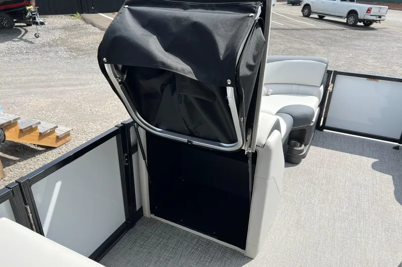 Slide: The Image of 2026 Tahoe TRITOON 2185 interior with seating and storage compartment, parked outdoors. - 18