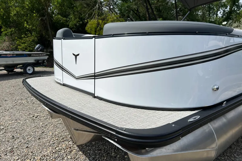 Slide: The Image of 2026 Tahoe TRITOON 2185 boat, sleek design, parked on gravel, with trees in background. - 5
