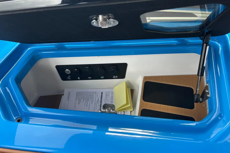 Slide: The Image of 2026 Nautique Super Air Nautique G23 storage compartment with control panel and documents. - 20