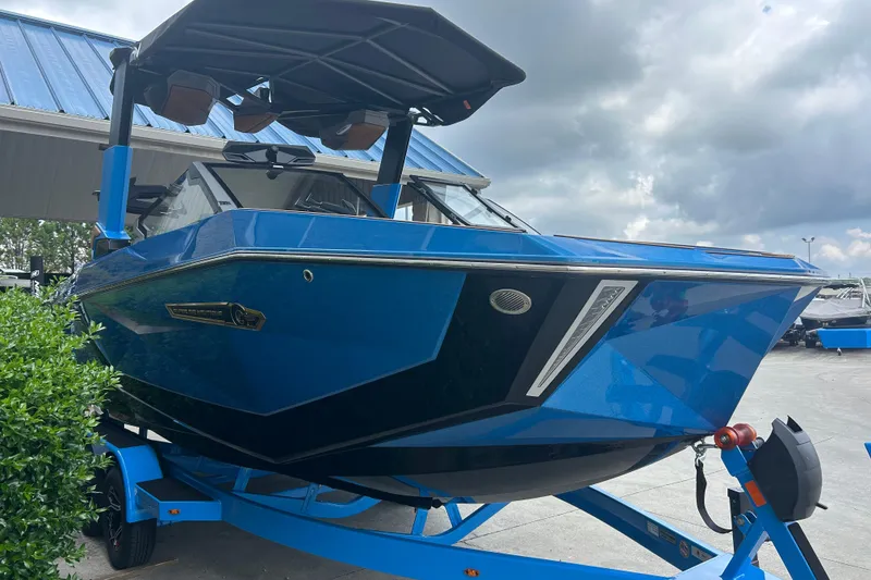 Slide: The Image of 2026 Nautique Super Air Nautique G23 boat in vibrant blue, parked outdoors under cloudy skies. - 3