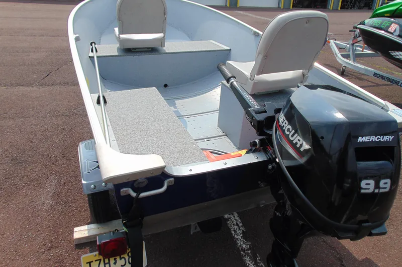 Slide: The Image of 2022 Crestliner 1261 Outreach boat with Mercury 9.9 motor, parked on asphalt. - 4