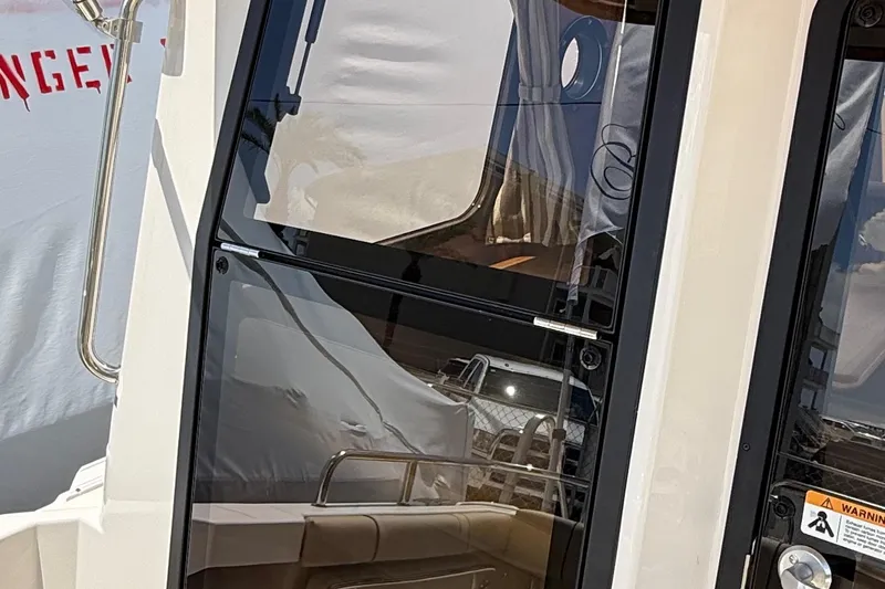 Slide: The Image of 2025 Ranger Tugs R-23 boat door with reflective glass and stainless steel handle. - 17