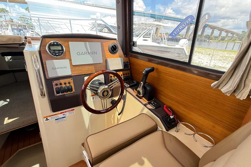 Slide: The Image of 2025 Ranger Tugs R-23 helm with Garmin navigation, wood accents, and comfortable seating. - 27