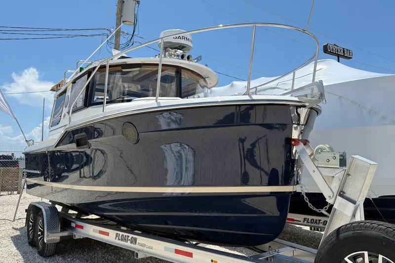 Slide: The Image of 2025 Ranger Tugs R-23 boat on trailer under clear blue sky. - 3