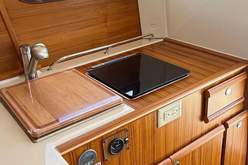 Slide: The Image of 2025 Ranger Tugs R-23 interior kitchen with wooden cabinetry and modern appliances. - 31