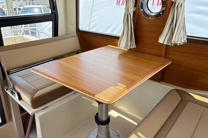 Slide: The Image of Interior of 2025 Ranger Tugs R-23, featuring a wooden table and cushioned seating. - 33