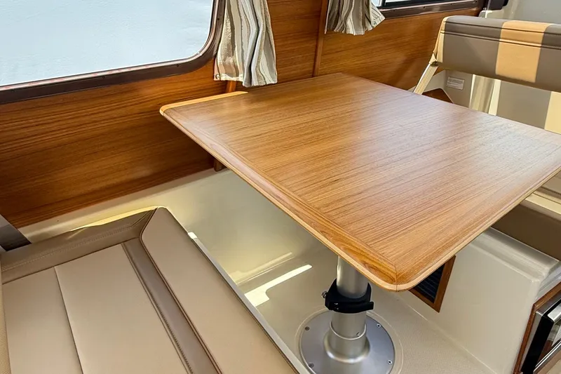 Slide: The Image of Interior of 2025 Ranger Tugs R-23, featuring a wooden table and cushioned seating. - 38