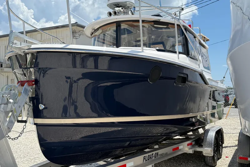 Slide: The Image of 2025 Ranger Tugs R-23 boat on trailer, sleek design, navy blue hull. - 4