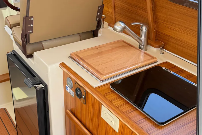 Slide: The Image of 2025 Ranger Tugs R-23 interior with kitchenette, featuring a sink, cutting board, and stove. - 41