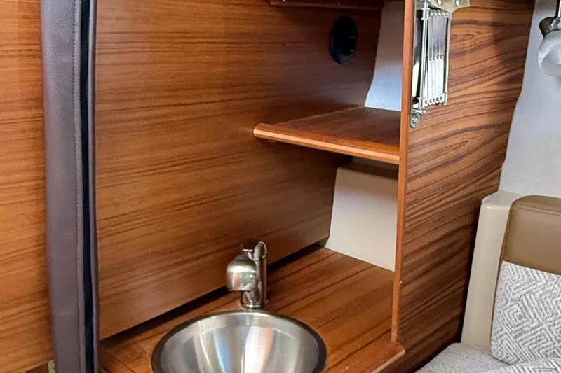 Slide: The Image of 2025 Ranger Tugs R-23 interior with wooden cabinetry and stainless steel sink. - 44