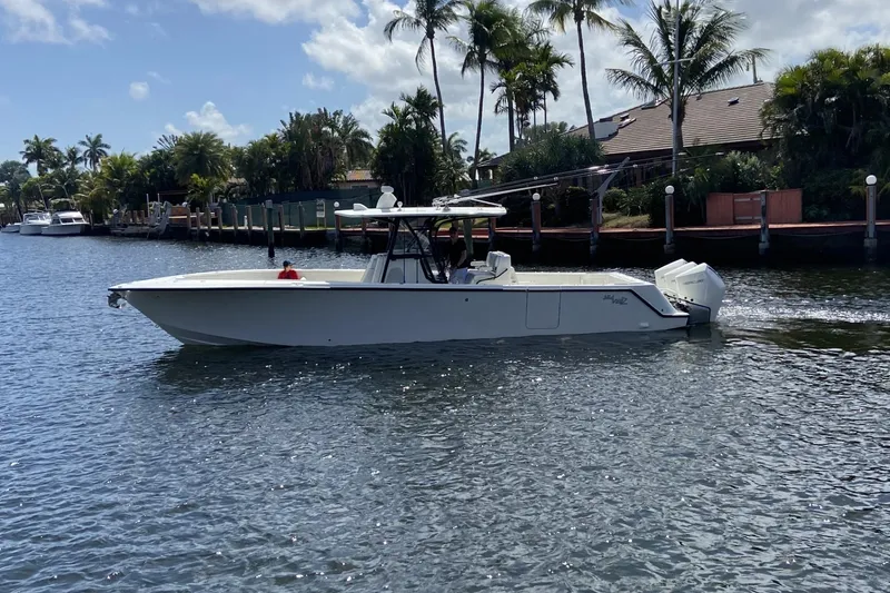 Slide: The Image of 2021 SeaVee 37 boat cruising on a sunny day near palm-lined waterfront homes. - 2