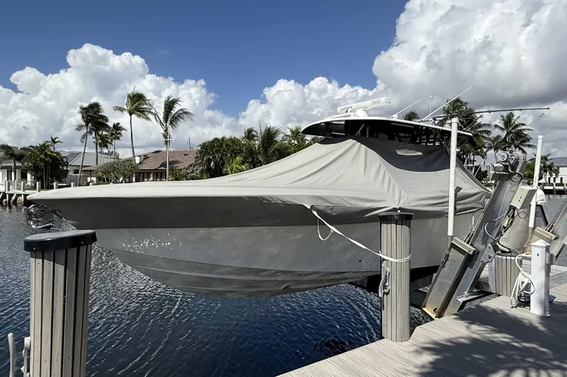Slide: The Image of 2021 SeaVee 37 boat covered and docked by palm trees under a cloudy sky. - 6