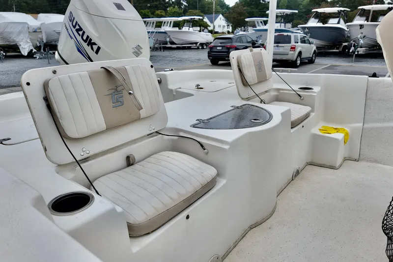 Slide: The Image of 2016 Carolina Skiff Standard 2180 boat interior with Suzuki engine, featuring seating and storage. - 6