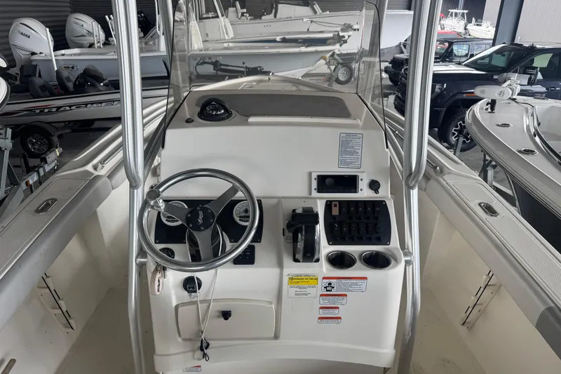 Slide: The Image of 2020 Mako 214 CC boat console with steering wheel and controls in a showroom. - 8