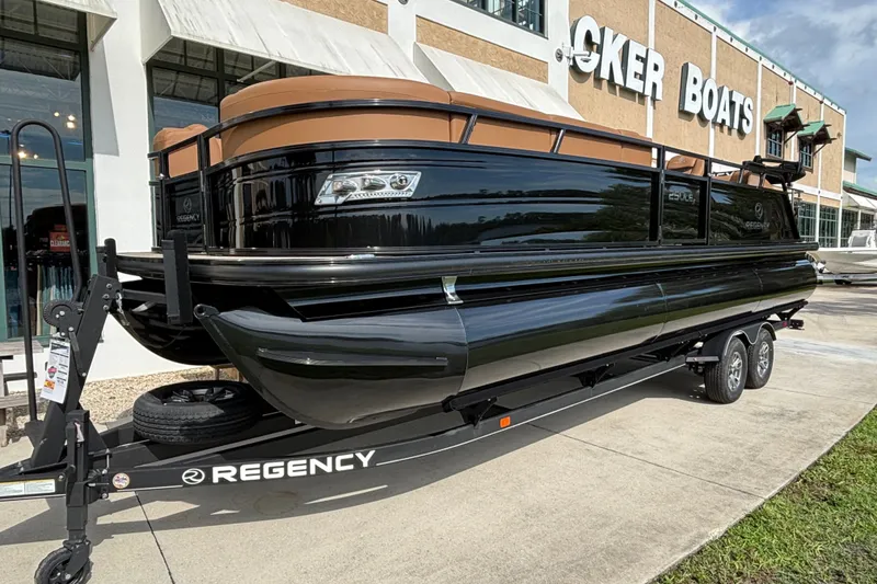 Slide: The Image of 2025 Regency 250 LE3 Sport pontoon boat on trailer outside Tracker Boats dealership. - 1