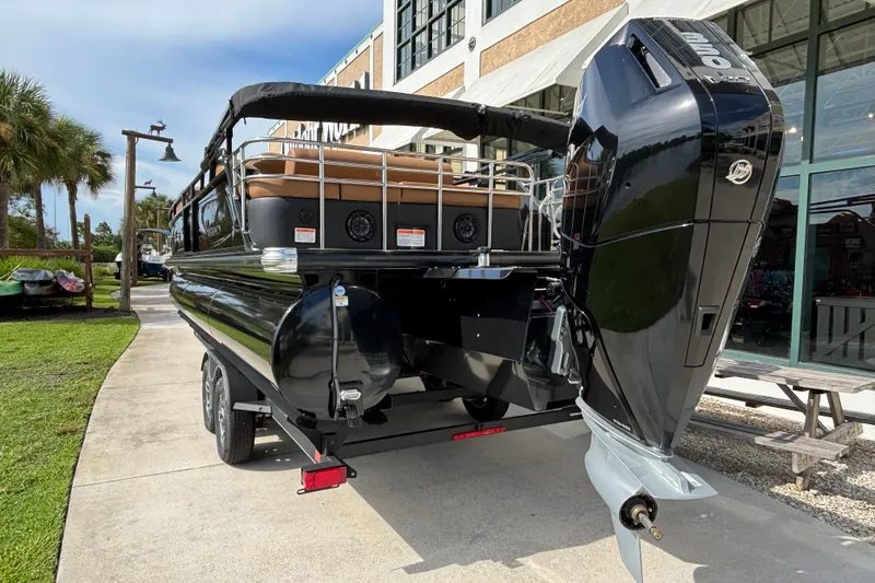Slide: The Image of 2025 Regency 250 LE3 Sport pontoon boat with powerful outboard motor, parked outdoors. - 3