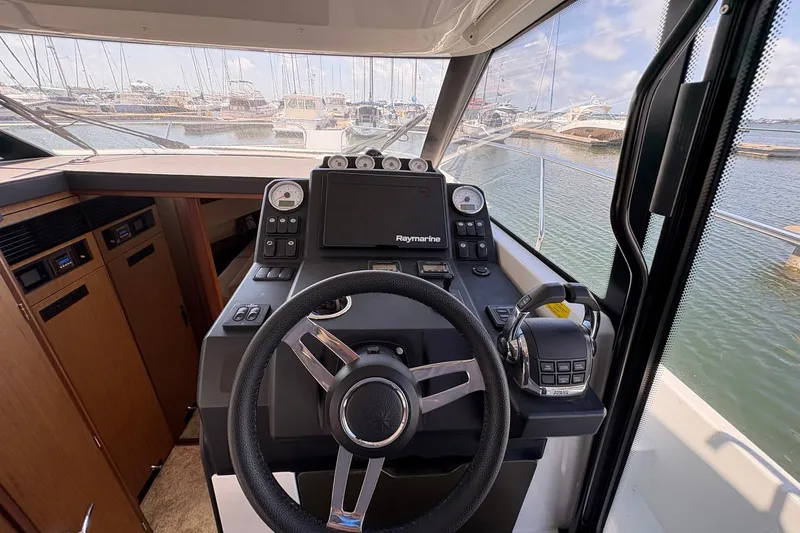 Slide: The Image of Cockpit view of 2019 Jeanneau NC 33 boat with steering wheel and navigation controls. - 11