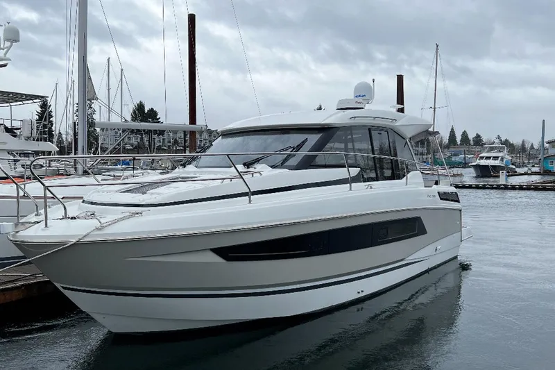 Slide: The Image of 2019 Jeanneau NC 33 yacht docked in a marina on a cloudy day. - 2