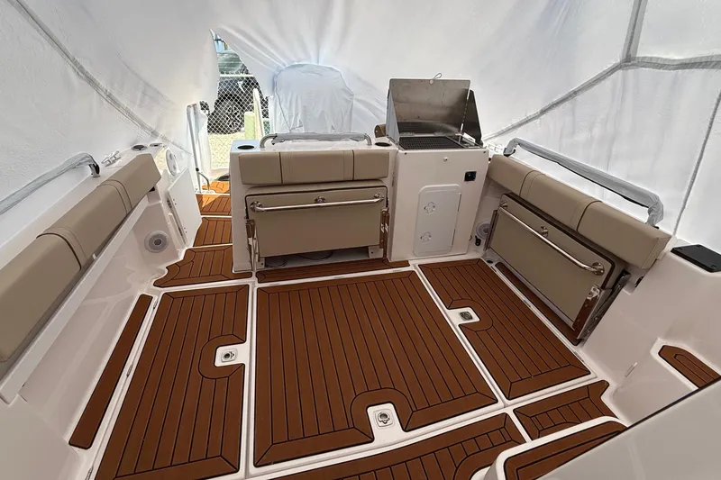 Slide: The Image of 2025 Ranger Tugs R-25 boat interior with teak flooring and cushioned seating. - 15