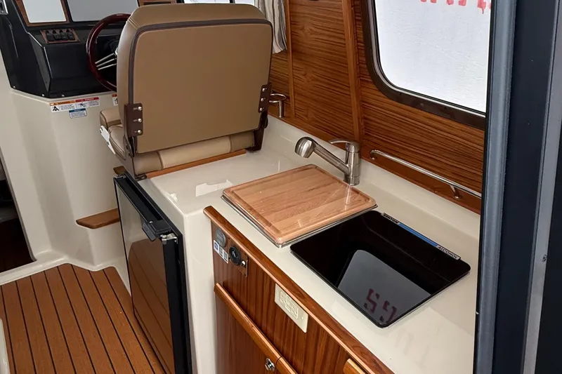 Slide: The Image of Interior of 2025 Ranger Tugs R-25, featuring helm, sink, and wooden cabinetry. - 28