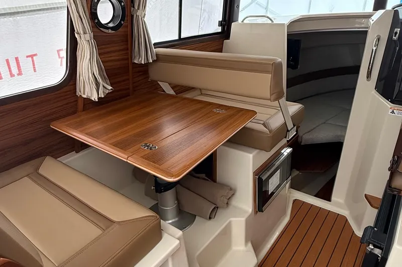 Slide: The Image of Interior of 2025 Ranger Tugs R-25, featuring a wooden table and beige seating. - 29