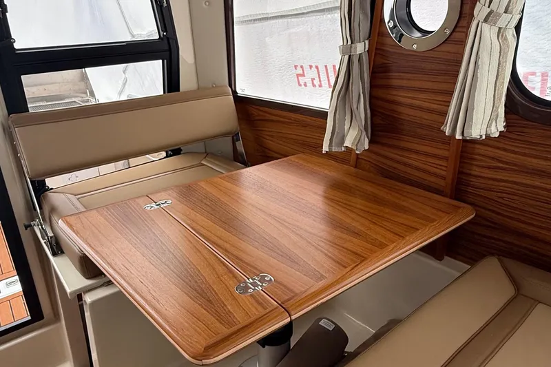 Slide: The Image of Interior of 2025 Ranger Tugs R-25 with wood table and beige seating. - 32