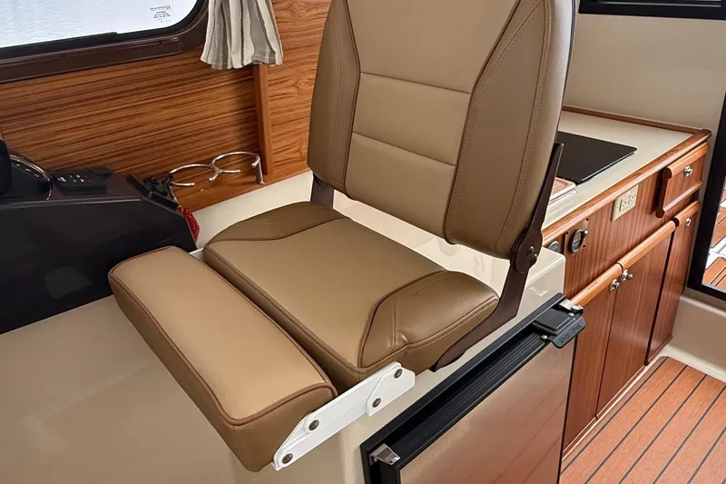 Slide: The Image of 2025 Ranger Tugs R-25 interior with tan seating and wooden cabinetry. - 37