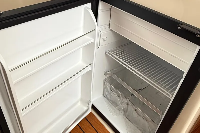 Slide: The Image of Open refrigerator inside 2025 Ranger Tugs R-25 boat, showcasing shelves and storage space. - 38